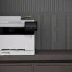 A sleek, modern printer situated on a minimalist office desk with a textured background.